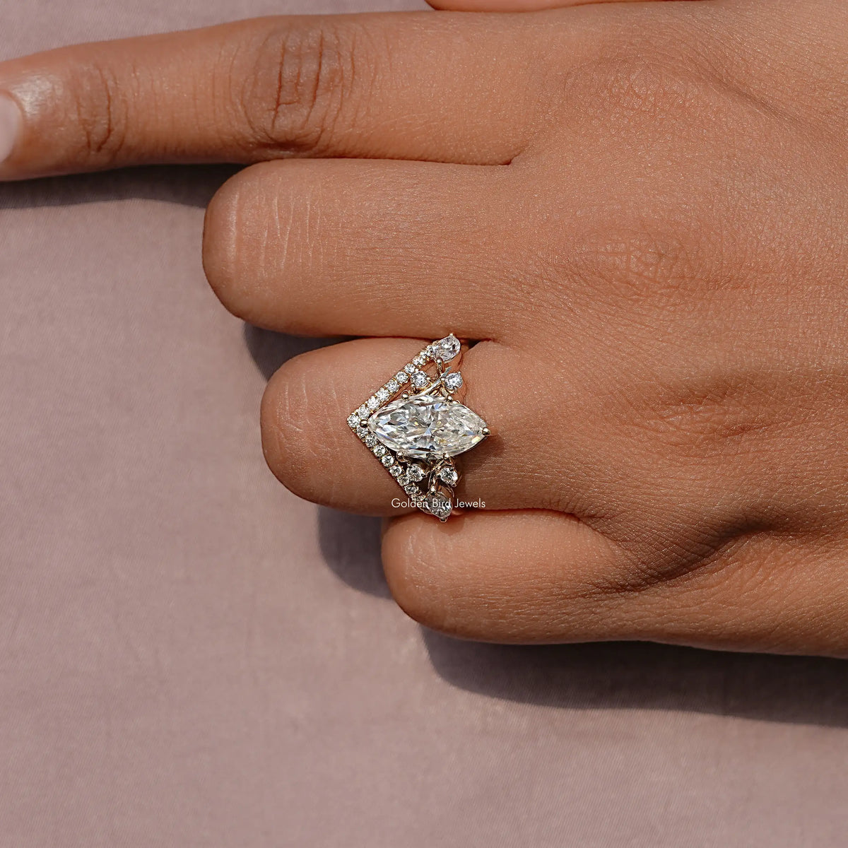 Gold-tone marquise cut cluster ring close-up with prong-set center and side stones