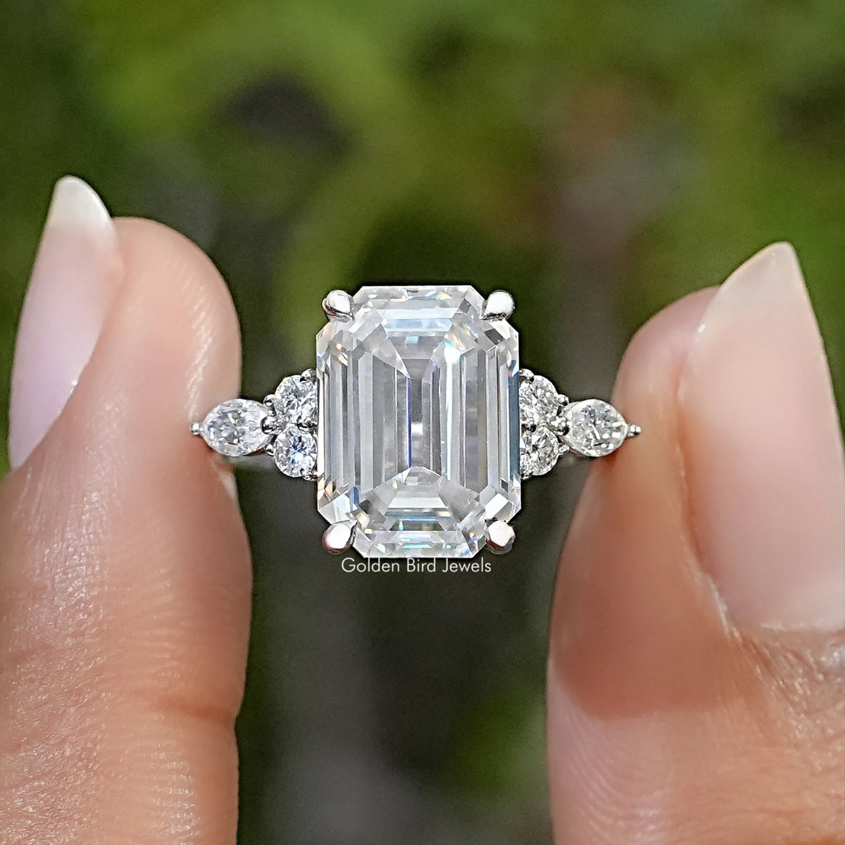 Sterling silver solitaire ring with a large emerald-cut moissanite and round accent stones.