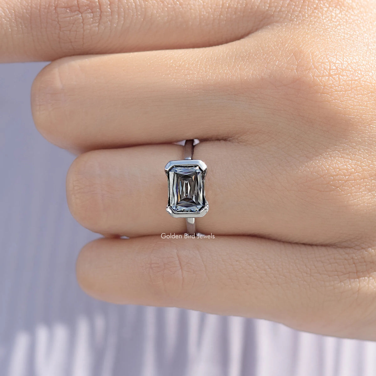 Close-up of sterling silver east-west moissanite solitaire ring with half bezel square stone
