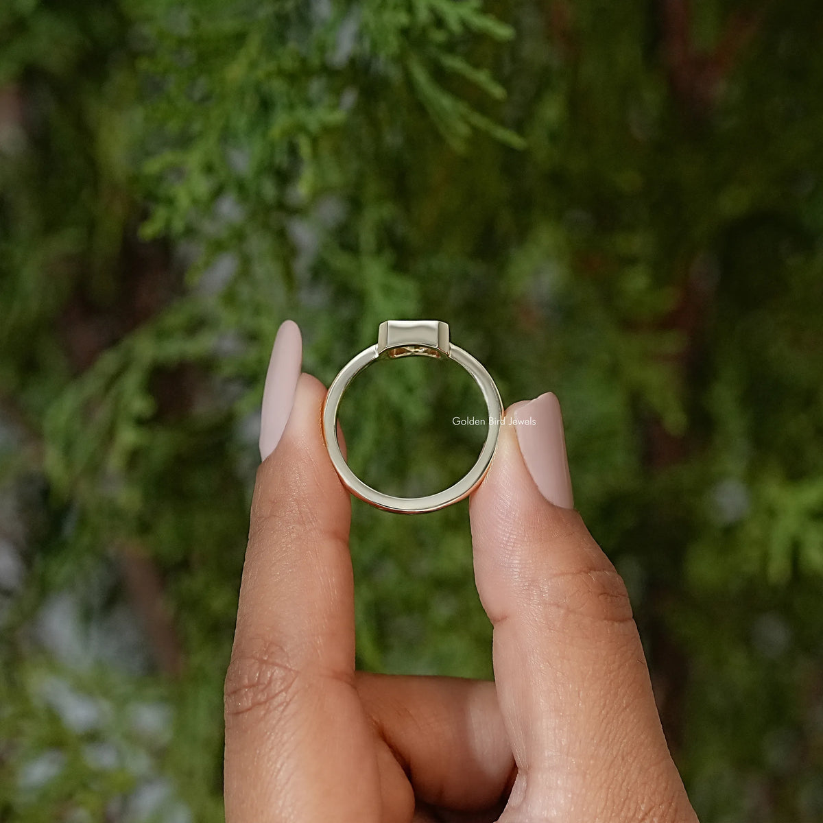 Gold-tone solitaire engagement ring, top view with bezel-set radiant-cut center
