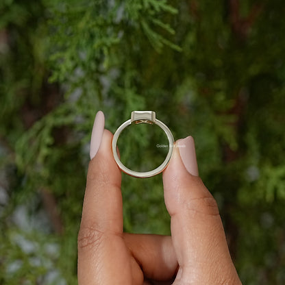 Gold-tone solitaire engagement ring, top view with bezel-set radiant-cut center