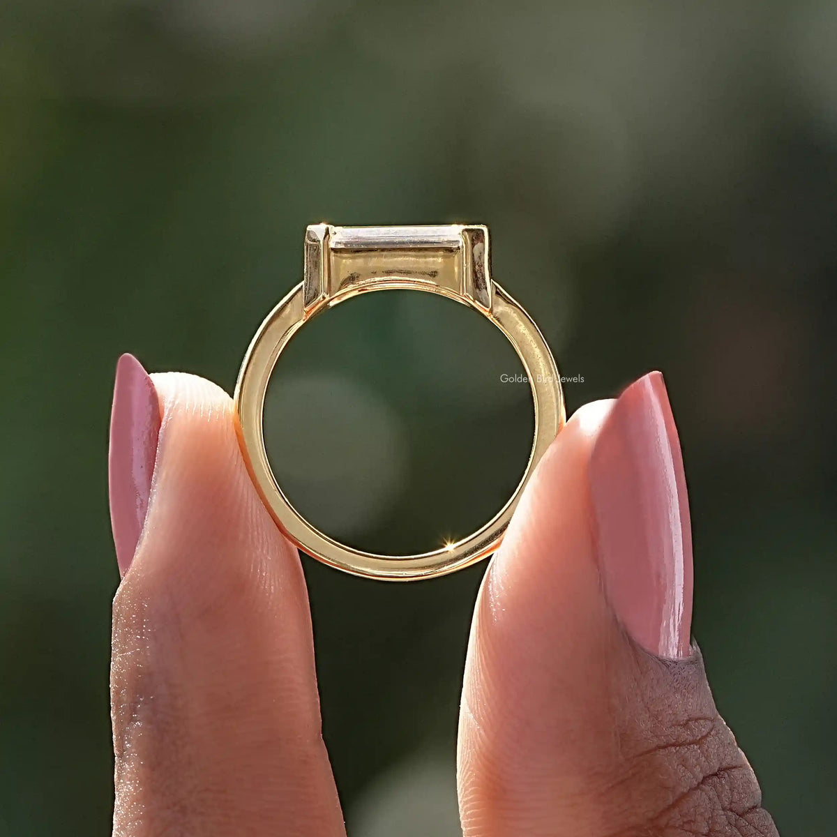 Emerald-cut solitaire ring top view, east-west stone in gold-tone prong setting