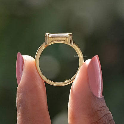 Emerald-cut solitaire ring top view, east-west stone in gold-tone prong setting