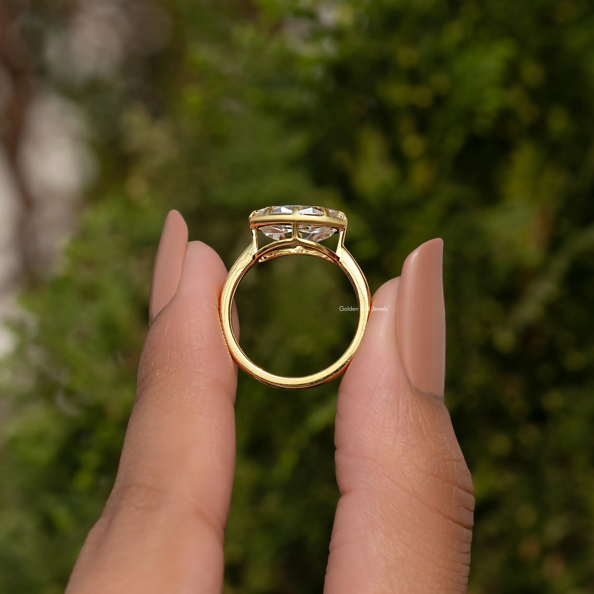 Oval moissanite solitaire ring showing the top view on fingers, gold-tone band.