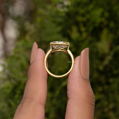 Oval moissanite solitaire ring showing the top view on fingers, gold-tone band.