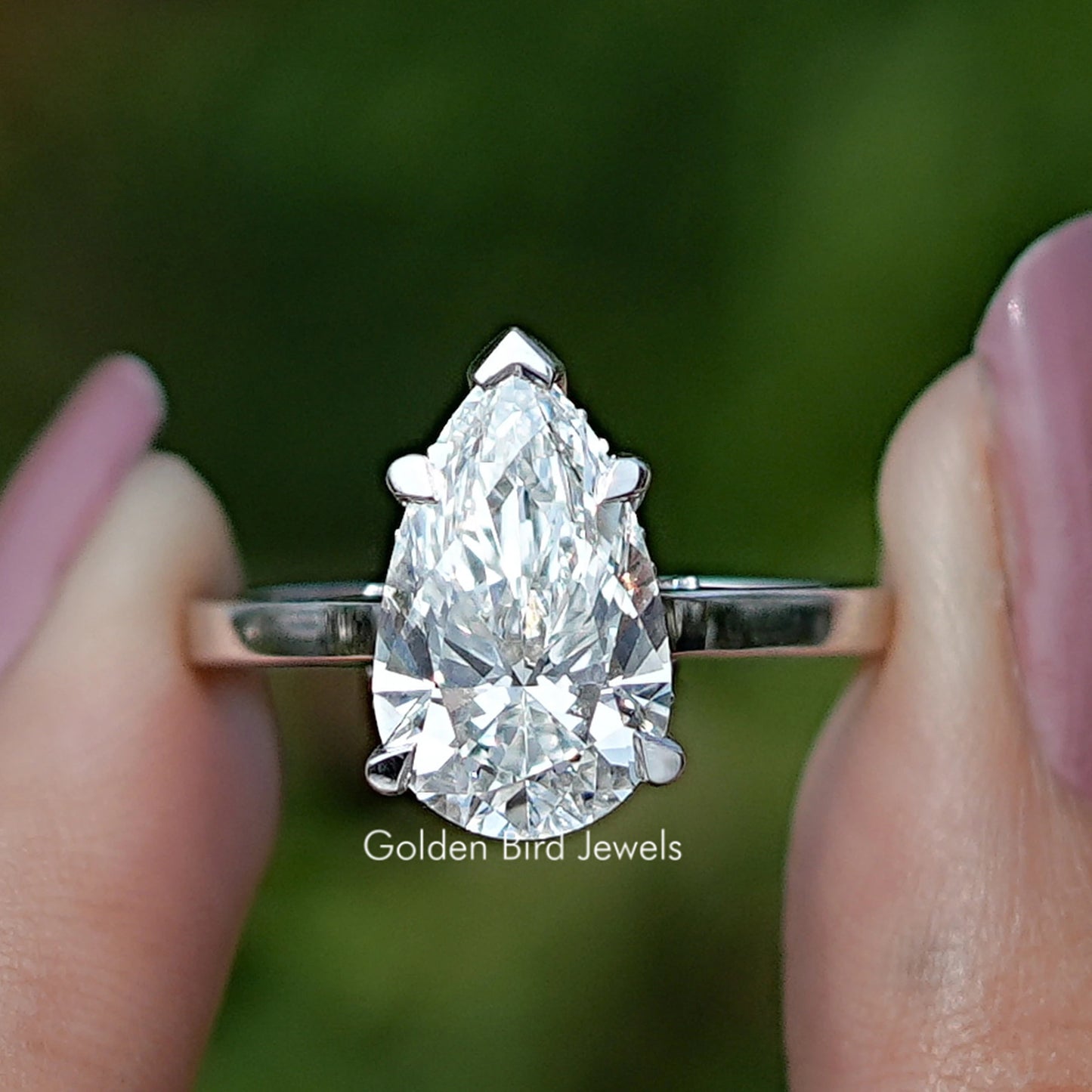 Pear Cut Halo Diamond Bridge Accent Wedding Ring Held Between Fingers