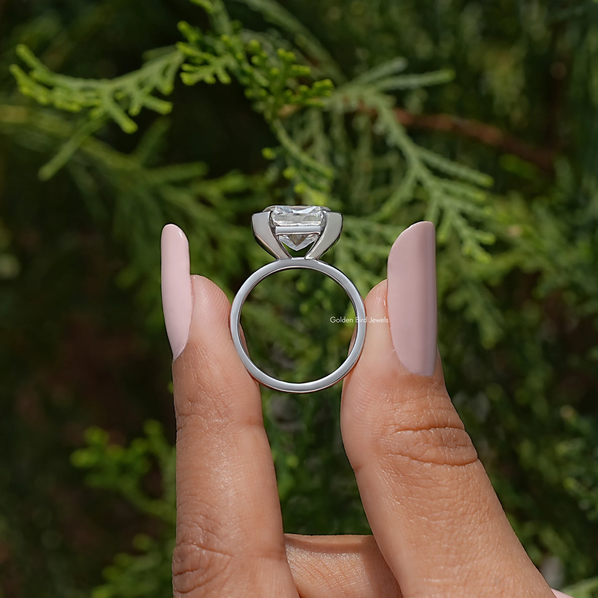 Moissanite solitaire ring with half-bezel setting on finger, side profile view