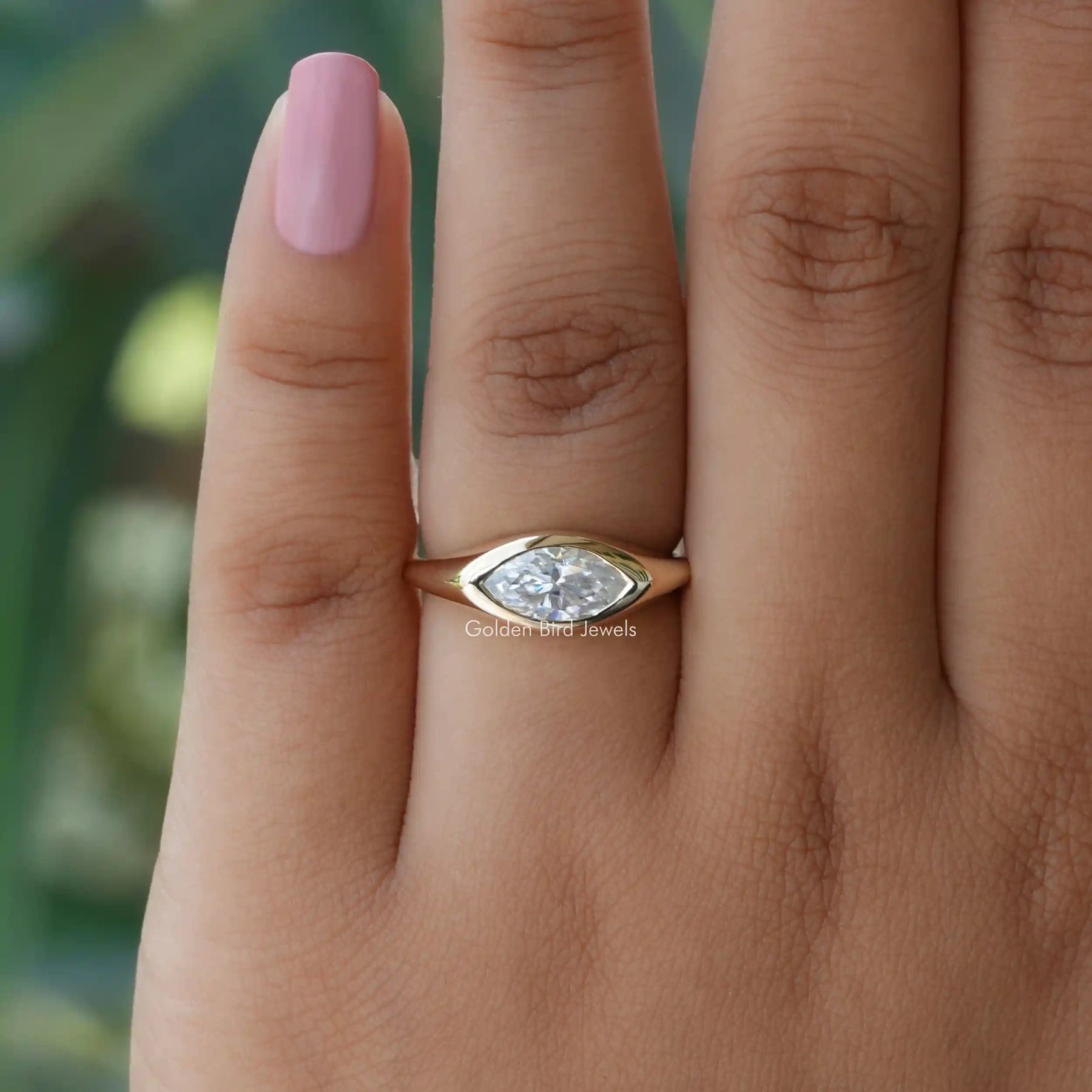 In finger top view of solitaire moissanite  engagement ring in fancy bezel set 