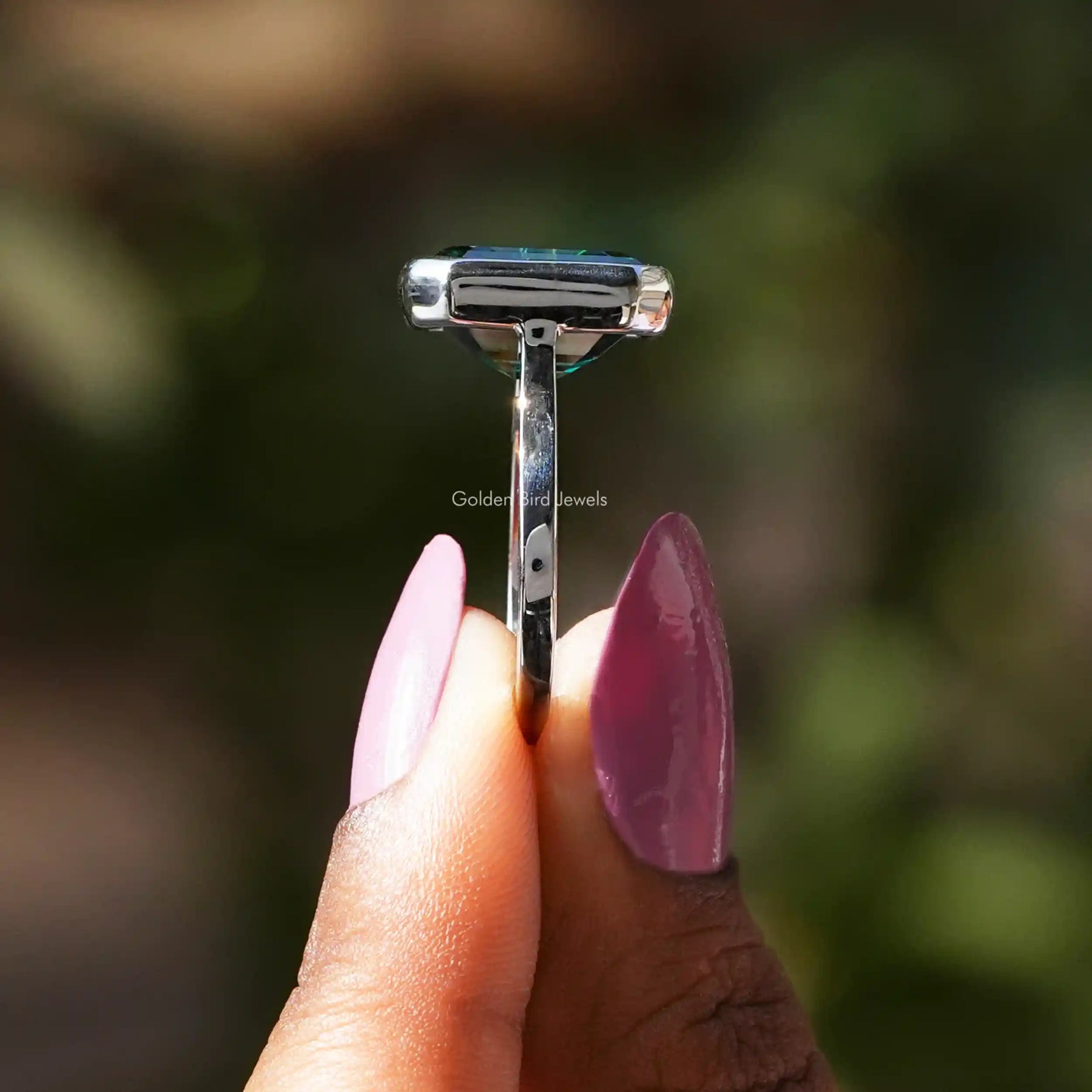 Side View of Green Emerald Cut Solitaire Ring In two fingers