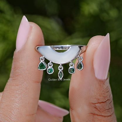 Curved bezel-set engagement ring with green oval and round gemstones, silver band