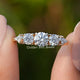 Kite And Round Cut Lab Diamond Five Stone Ring Held Between Fingers