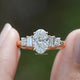Oval Cut Lab Diamond Five Stone Engagement Ring BetweenTwo Fingers