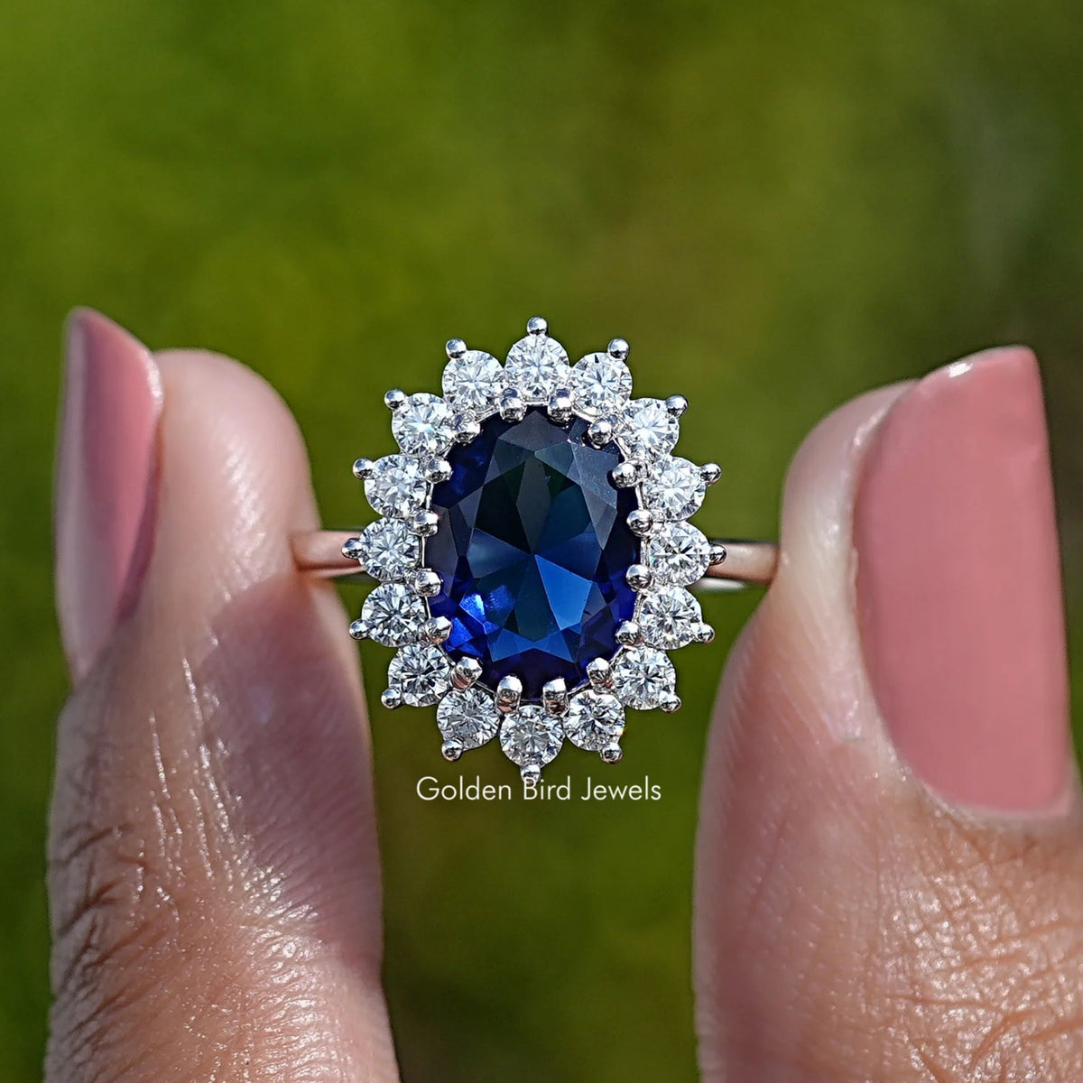 Oval gemstone halo engagement ring with dark blue center and round sparkle accents