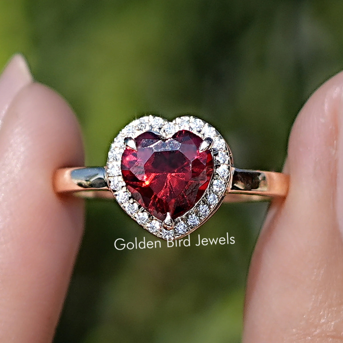 Front view of Red Ruby Heart Gemstone Halo Engagement Ring Set in two fingers 