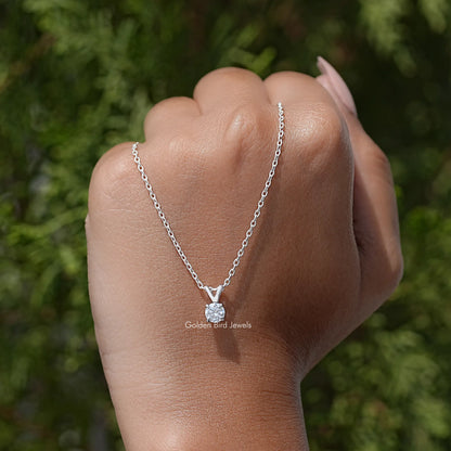 Silver round moissanite solitaire pendant on chain, worn on hand outdoors