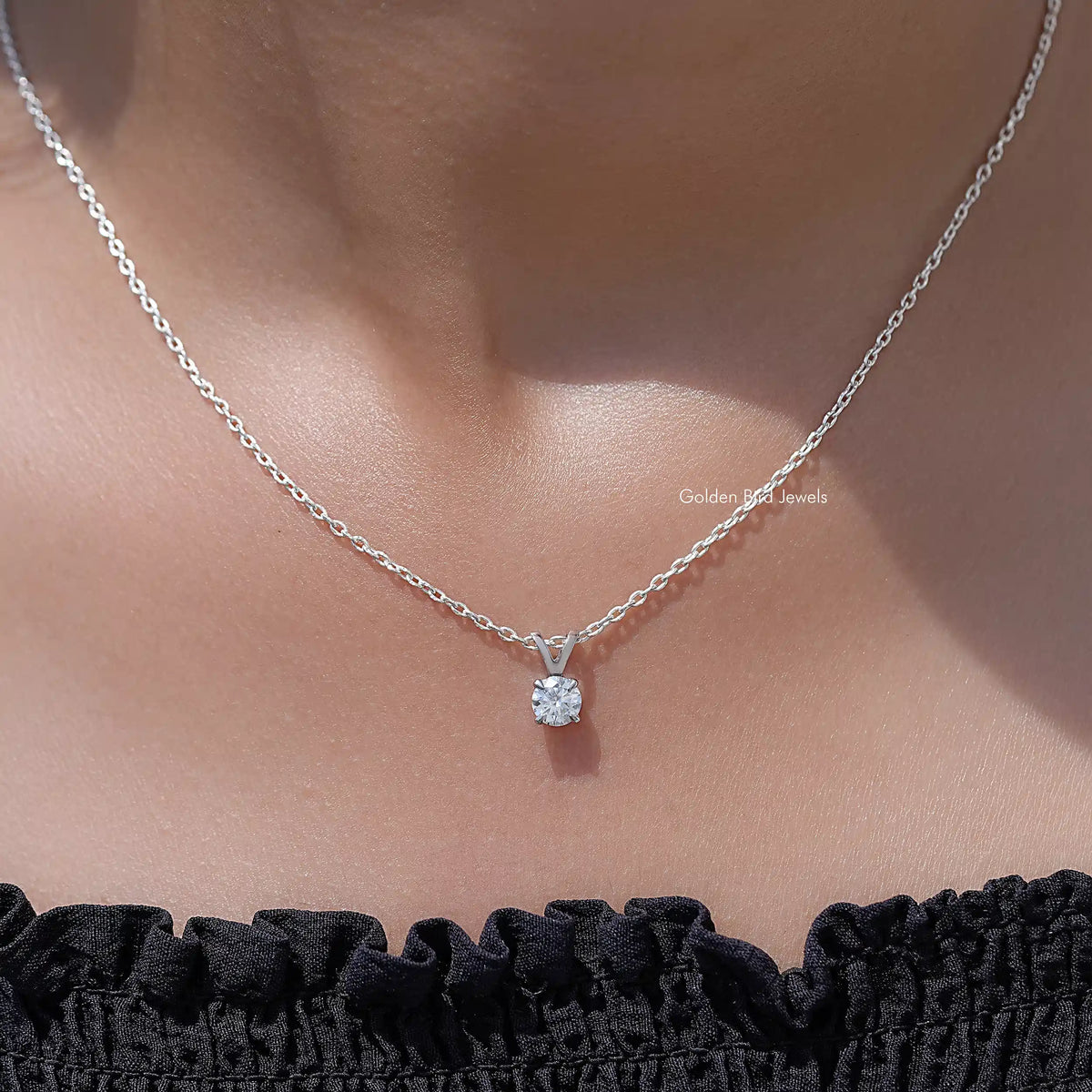 Silver chain necklace with round moissanite solitaire pendant, close to neckline